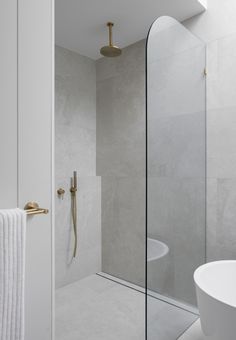 a bathroom with a glass shower door and gold fixtures on the wall, next to a white sink