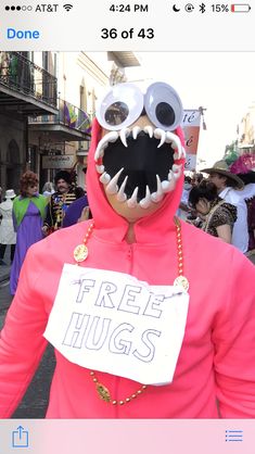 a person in a pink monster costume holding a sign that says free hugs on it