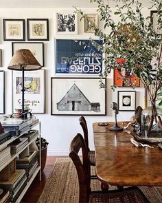 a dining room table with chairs and pictures on the wall