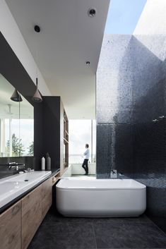 a bathroom with a large bathtub next to a sink and a person in the mirror