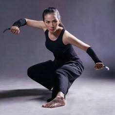 a woman in black shirt and pants holding a knife