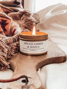 a candle sitting on top of a wooden table next to a cow skin pillow and blanket