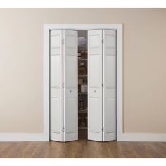 an empty room with two tall white closet doors open to reveal the pantry in the corner