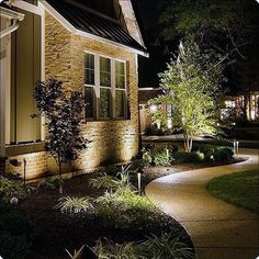 a house that is lit up at night with lights on the front and side of it