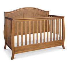 a wooden crib with white sheets on the bottom and sides, against a white background