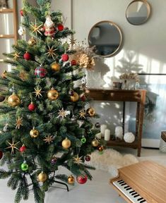 a small christmas tree with ornaments on it in front of a piano and other decorations