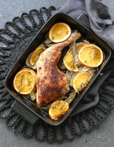 a roasting pan filled with chicken and sliced oranges on top of a table