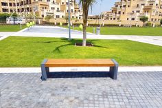 a wooden bench sitting on top of a brick walkway next to a lush green park