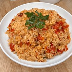 a white plate topped with rice covered in sauce and garnished with parsley