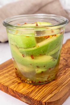 a glass jar filled with sliced avocado on top of a wooden cutting board