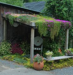 a wooden bench covered in plants next to a building