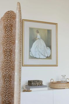 a painting hanging on the wall next to a white cabinet with a leopard print purse