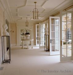 a hallway with white walls and doors leading to another room that has glass windows on both sides