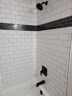 a white bath tub sitting next to a black and white tiled shower head in a bathroom