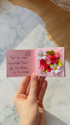 someone is holding an open card with flowers on it