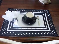 a black and white polka dot placemat with a cup, spoon and napkin on it