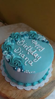 a blue birthday cake with white frosting on a wooden board and lace doily