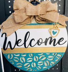 a welcome sign hanging on the side of a wooden door with burlocks and a bow