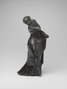 a bronze statue of a woman wearing a long dress and holding her hand on her hip