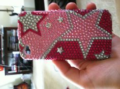 a hand holding up a pink case with silver stars on it