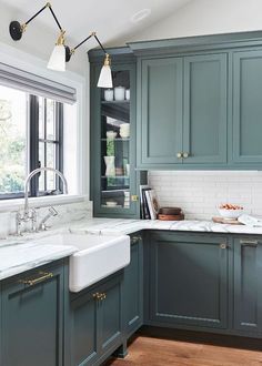 a kitchen with blue cabinets and marble counter tops, along with a white sink in the center