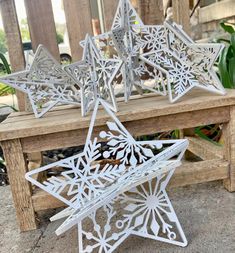 three metal snowflakes sitting on top of a wooden bench