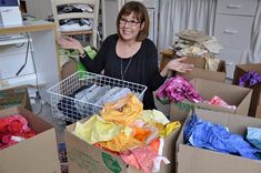 a woman standing next to boxes filled with clothes