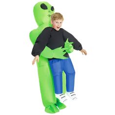 an inflatable costume with a boy standing next to a giant green alien balloon