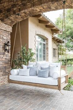 a porch swing with pillows on it