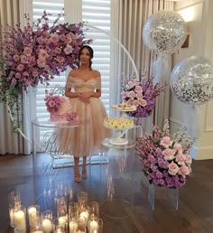 a woman standing in front of a table filled with cake and flowers