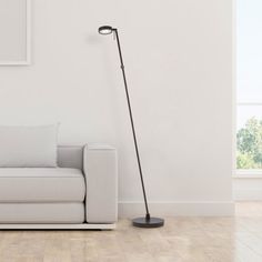 a living room with a white couch and a black floor lamp on the side of it