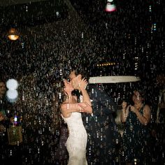 a bride and groom kissing in front of bubbles on the dance floor at their wedding