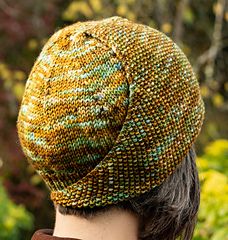 a close up of a person wearing a knitted hat with trees in the background