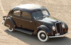 an old model car is parked in the dirt