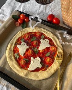 a homemade pizza with tomatoes, cheese and ghost decorations