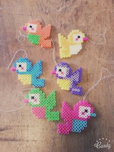 four little pony brooches hanging from string on a wooden table with strings attached to them