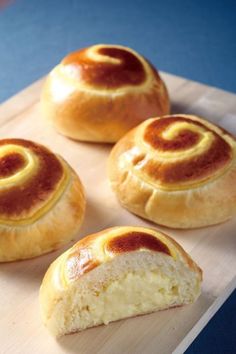 four rolls sitting on top of a wooden cutting board