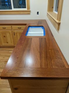 a wooden counter top in a kitchen next to cabinets and windows with blue trim on the edge