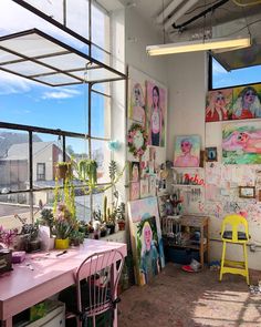 a room filled with lots of art and plants on the wall next to a window