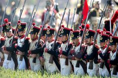 a group of men in uniform marching through the grass