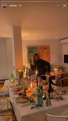 a woman sitting at a dinner table with candles on it