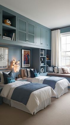 two beds in a room with blue and white decor on the walls, along with built - in bookshelves