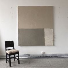 a chair sitting in front of a wall with a painting hanging on it's side