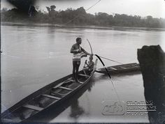 an old black and white photo of a man in a boat with two men standing on it