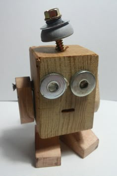 a wooden toy with two eyes and a button on it's head is shown