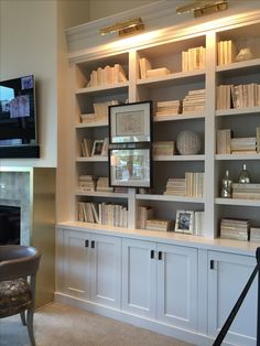 a living room filled with lots of white bookshelves next to a fire place