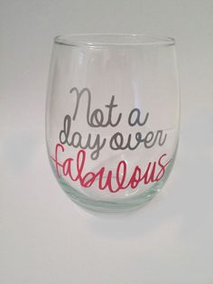 a wine glass that says not a day over fabulous on the inside and red writing on the outside