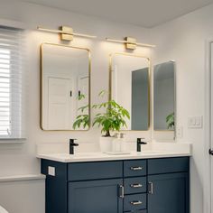 a white toilet sitting next to a bathroom sink under two large mirror mounted on the wall