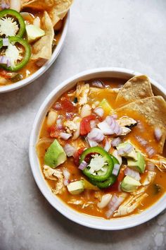 two bowls of soup with tortilla chips on the side and salsa in the middle