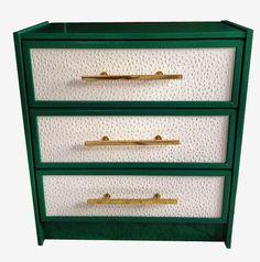 a green and white dresser with three drawers on it's sides, one drawer has gold handles